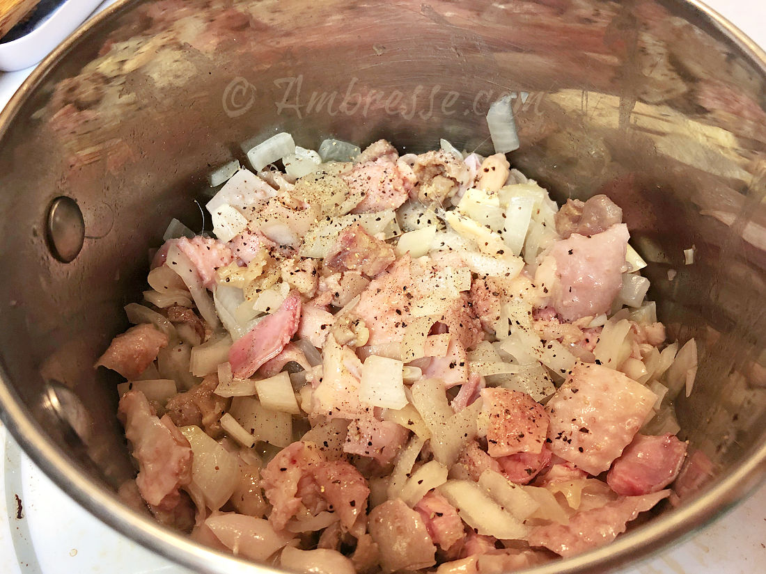 Chopped onion and chicken fat and pieces beginning to cook.